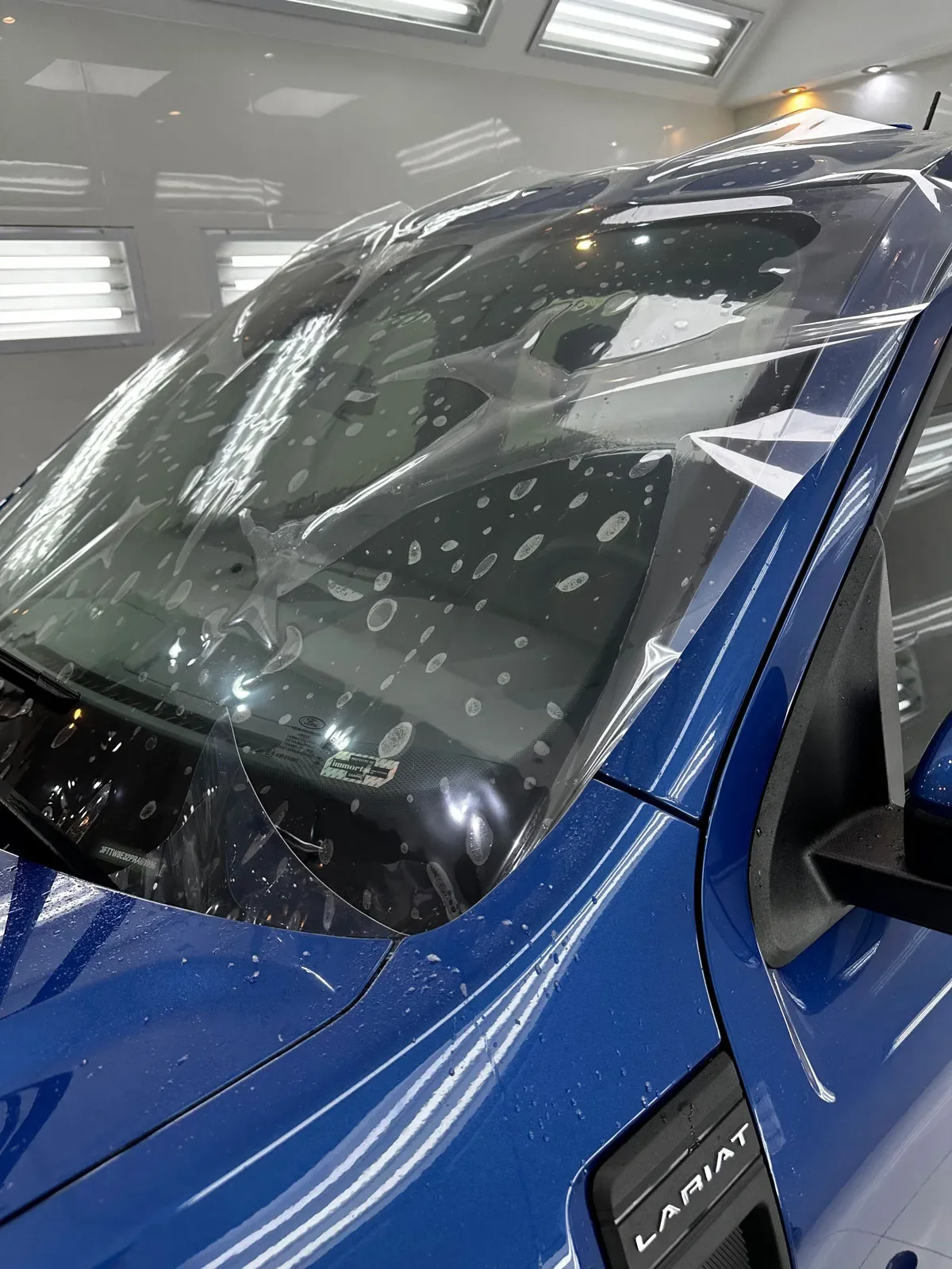 Parabrisas de una camioneta azul con film de protección durante la instalación en el taller de ADM TEAM