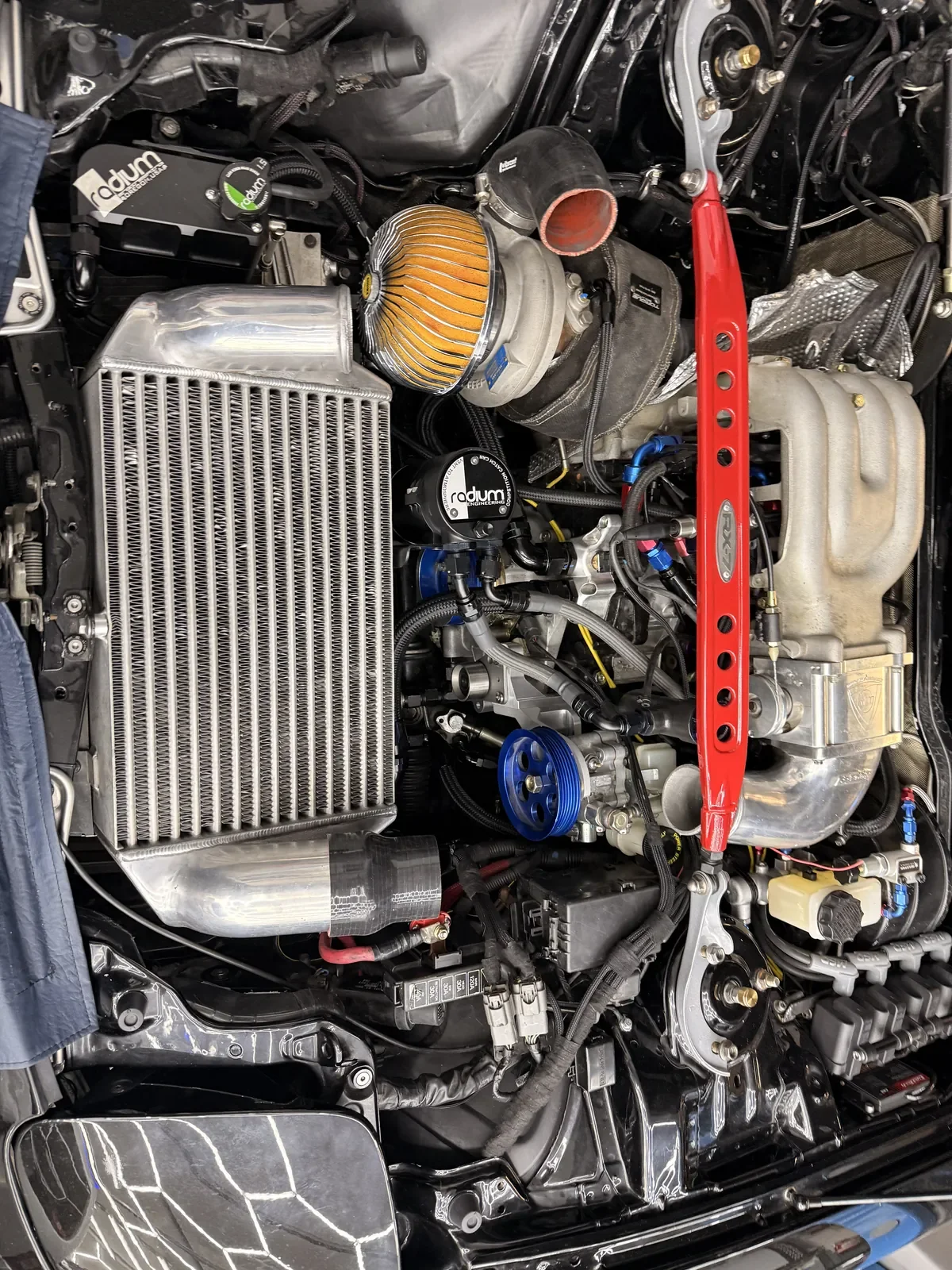 Vano motor del Mazda RX-7 FD con el intercooler montado, cañerías de aluminio y barra de torres roja