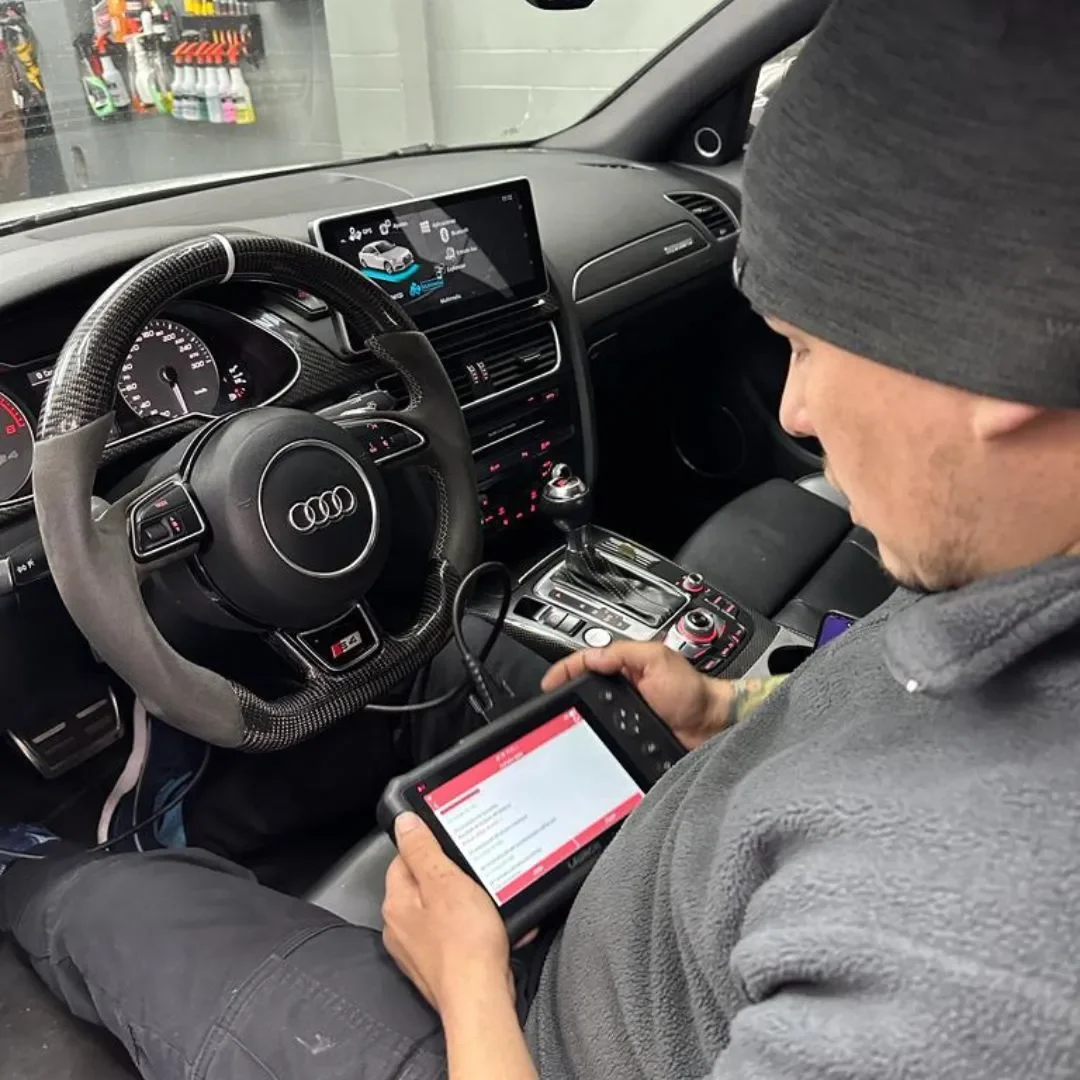 Técnico de ADM TEAM leyendo fallas con un scanner de diagnóstico dentro de un auto