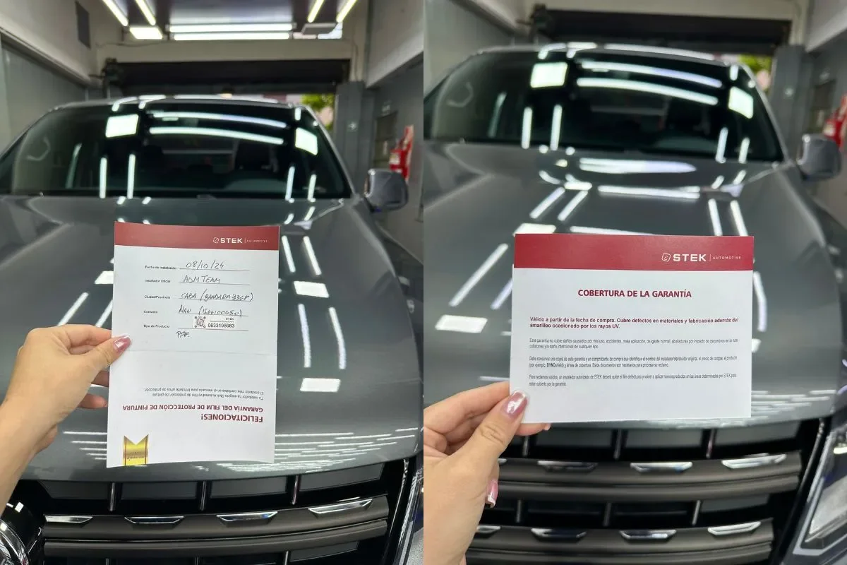 Certificado de garantía STEK completado por ADM TEAM como instalador oficial en CABA, sostenido sobre el capot de una camioneta gris con PPF